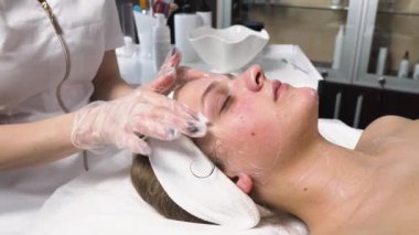 Kozmetik uzmanı müşterinin yüzünü güzellik salonunda jöle ile temizler..