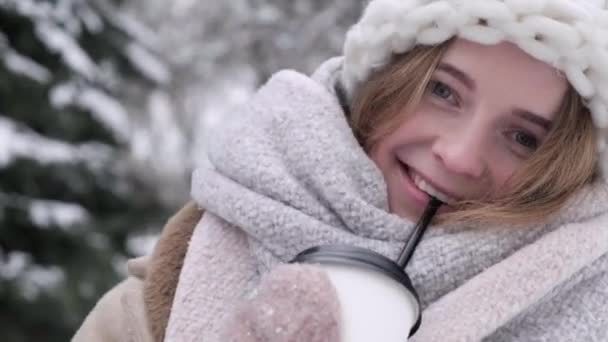 Giovane donna bionda felice al parco che beve una bevanda calda. Un inverno freddo e nevoso. — Video Stock