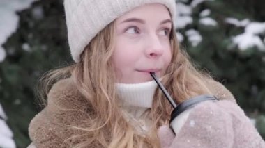 Sarışın soğuk kışta dışarıda sıcak bir kokteyl içer ve gülümser..