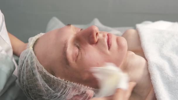 Les mains d'un cosmétologue font un massage facial à un jeune homme. — Video