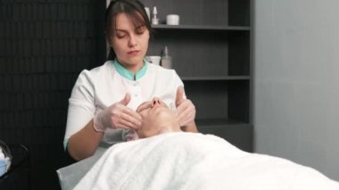 Kozmetik uzmanı kadın elleri kuaförde genç bir adama yüz masajı yapıyor..
