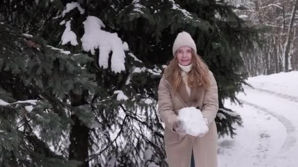 Молода вродлива жінка викидає великий клубок снігу. Зимові ігри. — стокове відео