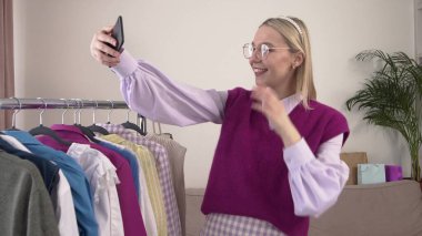 Elinde akıllı telefon olan bir kadın video bağlantısıyla internetten gözlük deniyor..