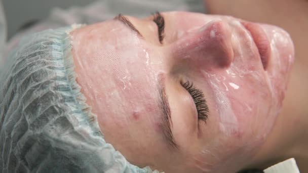 Die Kosmetikerin trägt einer jungen Kundin einen Gelpinsel auf das Gesicht auf. — Stockvideo