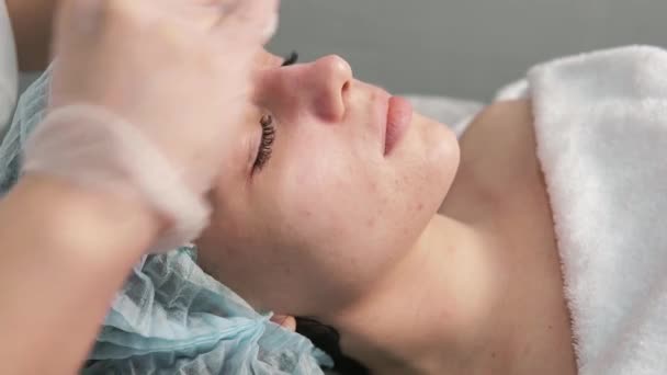 Egy profi kozmetikus tisztítja meg egy fiatal nő arcát pamut párnákkal.. — Stock videók