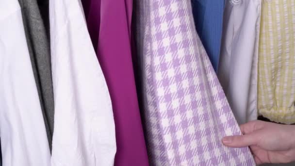 Hände suchen sich Kleidungsstücke auf dem Kleiderbügel für einen trendigen Look aus. Pinkfarbene Jacke im Karo. — Stockvideo
