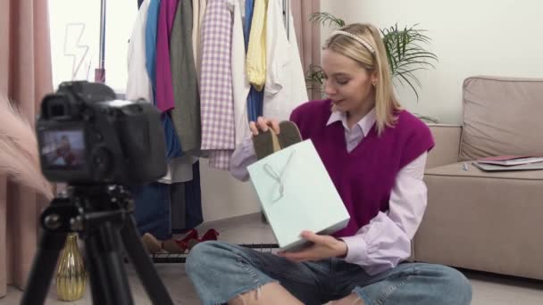 Egy nő, aki ül, elővesz egy ajándékot egy táska tornacipőből a kamera előtt.. — Stock videók