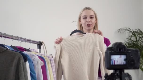 Mujer estilista muestra y habla de ropa hecha a mano delante de la cámara. — Vídeos de Stock