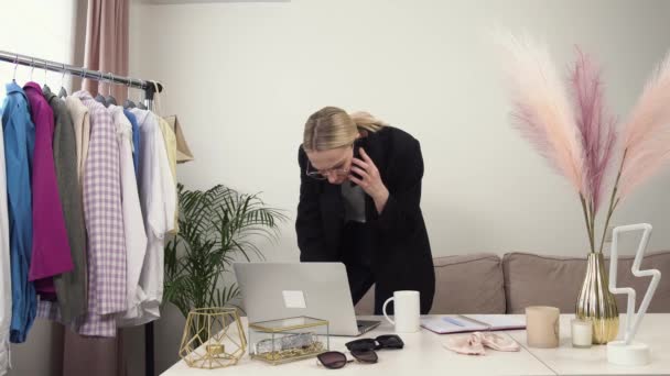 Una hermosa mujer con una chaqueta negra está hablando en un teléfono inteligente en la oficina. — Vídeos de Stock