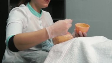 Kozmetik uzmanı müşterilerin yüzüne portakal yağı sürüyor. Güzellik salonu.