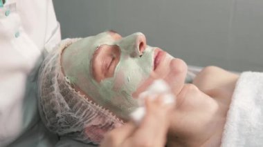Kozmetikçi, adamın yüzündeki doğal kilden peçeteyle kurtulur..