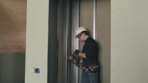 Un uomo lavora con una smerigliatrice angolare in un casco e occhiali di sicurezza. 4k video. — Video Stock