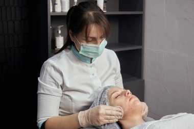 Güzellik salonunda profesyonel cilt bakımı. Bir kadın müşterisinin yüzünü temizler..