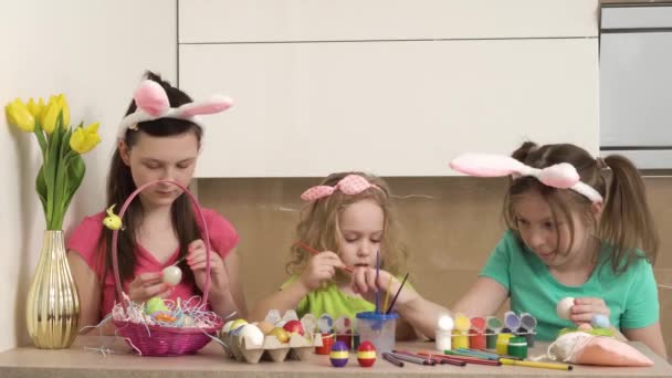 Tři dívky malují velikonoční vajíčka štětcem a štětcem. Video 4k.