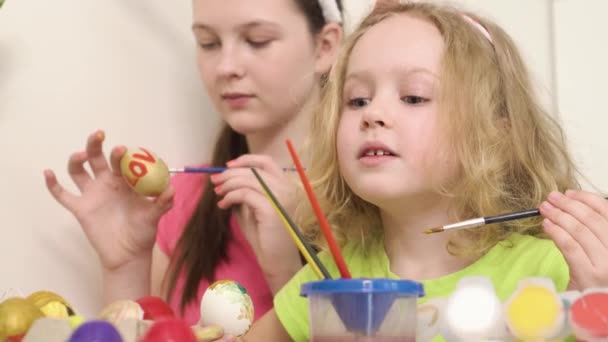 Mała dziewczynka bawi się pędzlem do farby. Dziewczyny malują jajka na Wielkanoc. — Wideo stockowe
