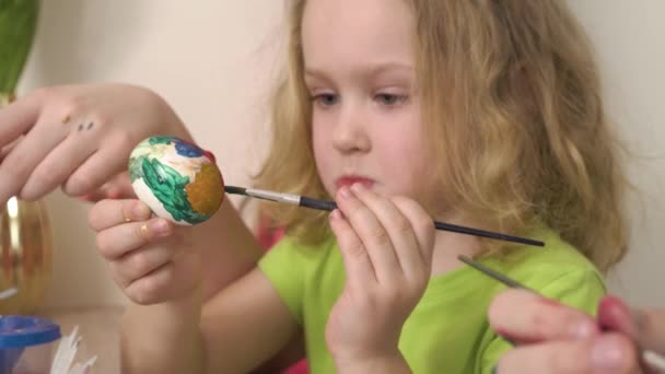 Zbliżenie cute girl malowanie pisanki z pędzlem i farbą. — Wideo stockowe