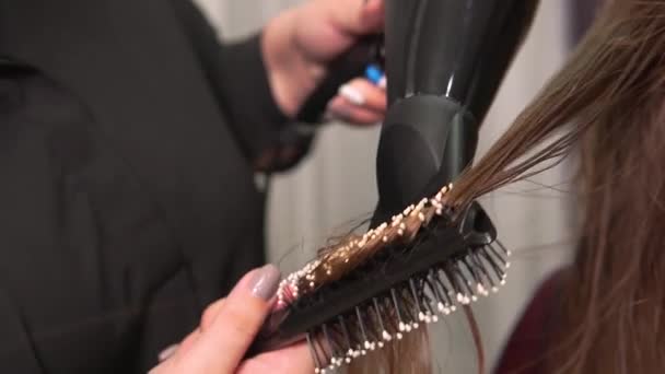 Κοντινό πλάνο ενός κομμωτή που στεγνώνει τα μαλλιά του με πιστολάκι μαλλιών, μια στρογγυλή βούρτσα μαλλιών. — Αρχείο Βίντεο