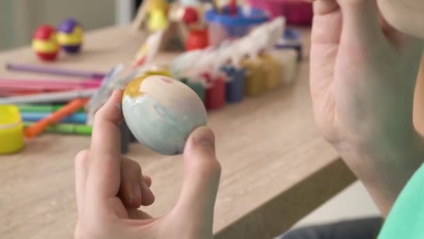Zbliżenie dziewczyny ręce malowanie wielkanocne jajko z farbą i pędzlem. — Wideo stockowe