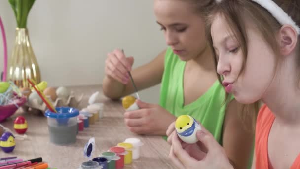 Meninas decorar ovos de Páscoa juntos. Tintas e marcadores estão na mesa. — Vídeo de Stock
