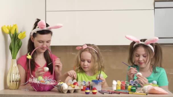 Niedliche Mädchen bemalen Ostereier in Hasenohren mit Farbe. 4k-Video. — Stockvideo