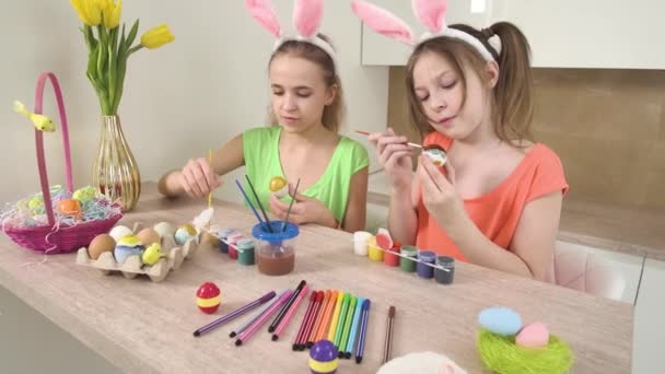 Le ragazze con le orecchie di coniglio sulla testa decorano le uova di Pasqua con vernice. — Video Stock