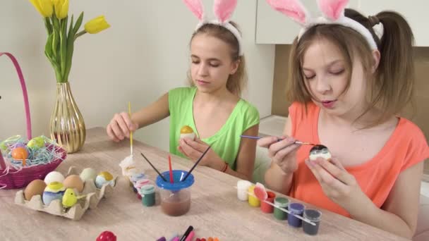 Två systrar dekorera påskägg med färger och hjälpa varandra. Påsk semester — Stockvideo