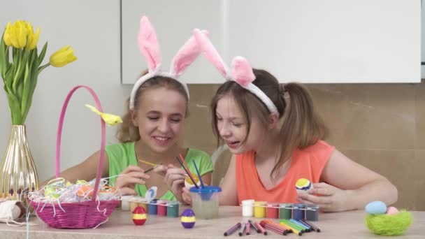 Dziewczyny ozdabiają wielkanocne jajka i pomagają sobie, rozmawiają i śmieją się. Święta wielkanocne. — Wideo stockowe