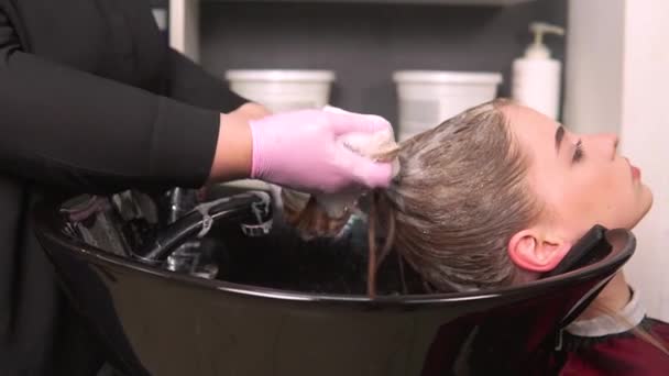 Kadeřník pěny šampon na mokré vlasy klienta v umyvadle. — Stock video
