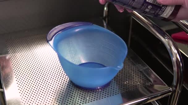 Da una grande lattina di vernice ad un altro contenitore di miscelazione. Ciotola di plastica con tintura per capelli. — Video Stock