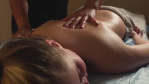 Uma jovem mulher bonita gosta de uma massagem nas costas. O conceito de relaxamento. — Vídeo de Stock