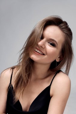 Güzel, genç, esmer kadın gülümseyip kameraya bakıyor..