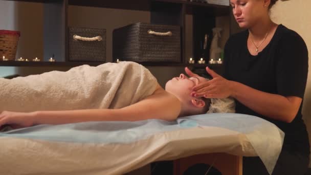 Eine Frau genießt eine Gesichtsmassage in einer Schönheitsklinik. Anti-Stress in der Therme. — Stockvideo