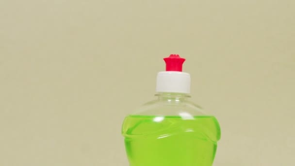 Зеленое средство для мытья посуды и две моющие губки. Светлый фон. — стоковое видео