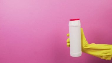 A hand in a glove with a white bottle with a red lid with household chemicals.