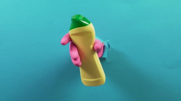 In the torn hole, a hand in a glove holds a yellow bottle of household chemicals — Stock video