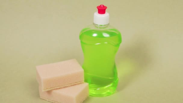 Detergente de prato verde em uma garrafa clara e duas esponjas. Fundo de luz. — Vídeo de Stock