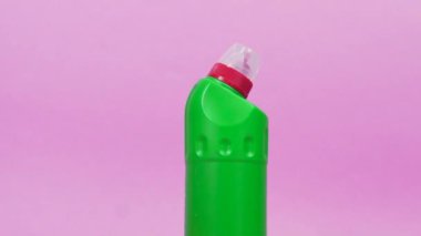 Plastik bir şişe temizleyici, lateks eldivenler ve temiz bir bez. Pembe arkaplan