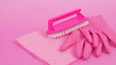 Toz bezi, lastik lateks eldiven ve pembe plastik fırça. Pembe arkaplan.