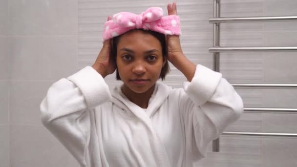 Афроамериканка накладає пов'язку на волосся, щоб помити обличчя.. — стокове відео