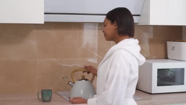 A young sleepy woman is making coffee in a white lab coat in the kitchen. — Stock Video