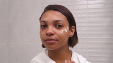 Nemlendirici ve besleyici krem kullanan genç bir kadının yakın çekimi..