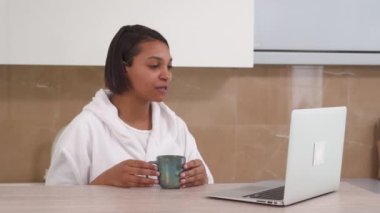 Bir Afro-Amerikalı kadın internetteki video bağlantısıyla bilgisayar kullanarak iletişim kuruyor..