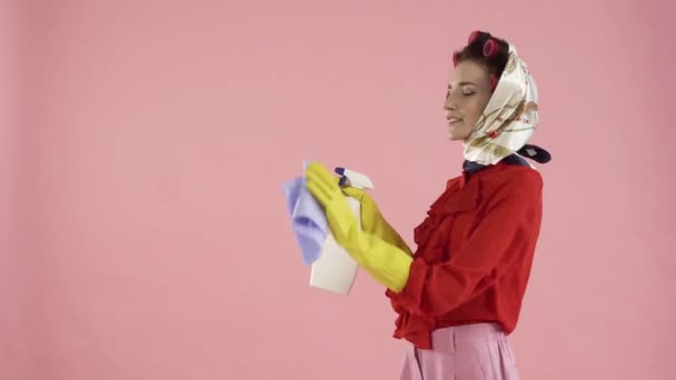 Una mujer con un pañuelo en la cabeza y rizadores lava una ventana invisible. — Vídeos de Stock