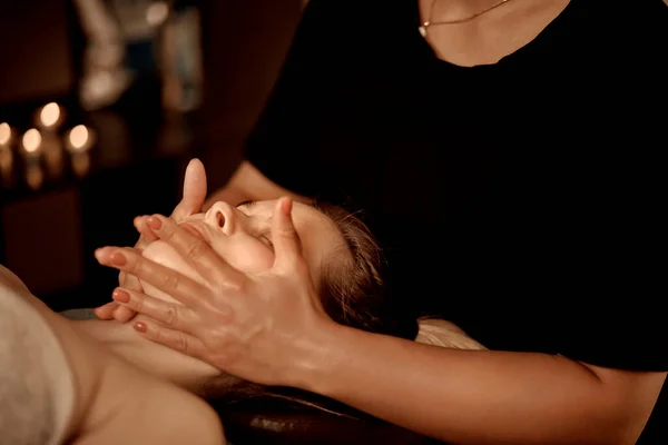 Una masajista le da un masaje facial a una joven. Masaje Wellness. — Foto de Stock