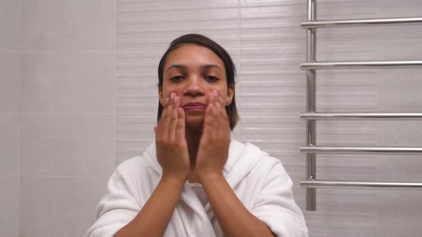 Młoda kobieta o ciemnej skórze myje twarz zimną wodą. Poranne zabiegi — Wideo stockowe