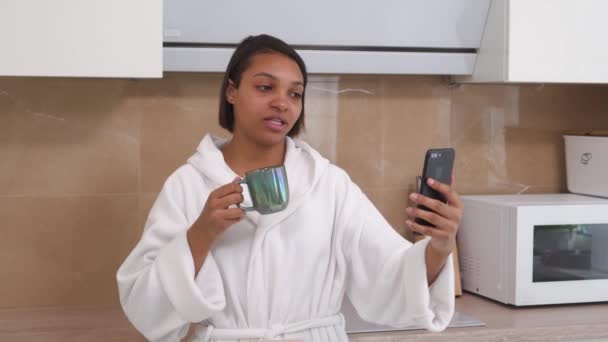 En afroamerikansk kvinna kommunicerar online via videolänk med hjälp av en smartphone. — Stockvideo