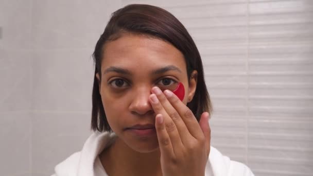 La mujer usa parches en los ojos rojos, antiarrugas. Hidratación de la piel. Tratamientos matutinos. — Vídeo de stock