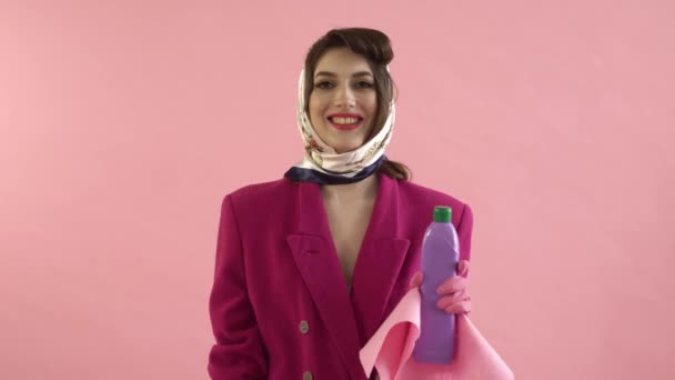 Una mujer con guantes de látex sostiene una botella de productos químicos domésticos y un trapo. — Vídeo de stock