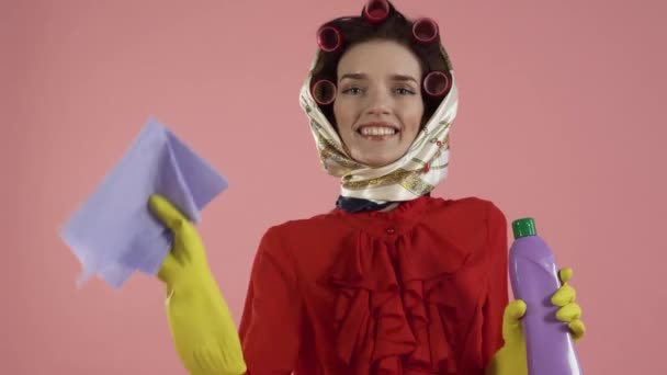 A woman with curlers on her hair cleans an invisible surface with a cloth. — Stock Video