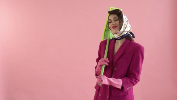 Uma jovem mulher de luvas de borracha está segurando uma esfregona verde brilhante em suas mãos. — Vídeo de Stock